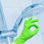 Hand with green gloves cleaning a shower