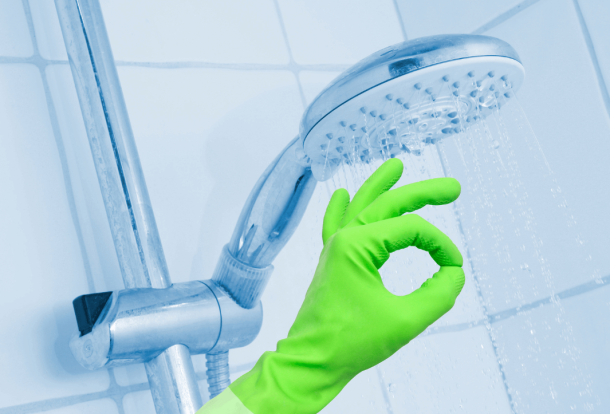 Hand with green gloves cleaning a shower