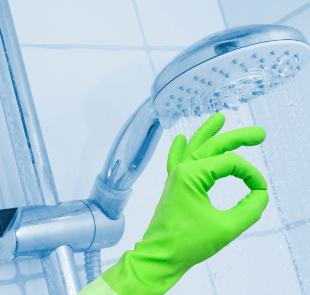 Hand with green gloves cleaning a shower
